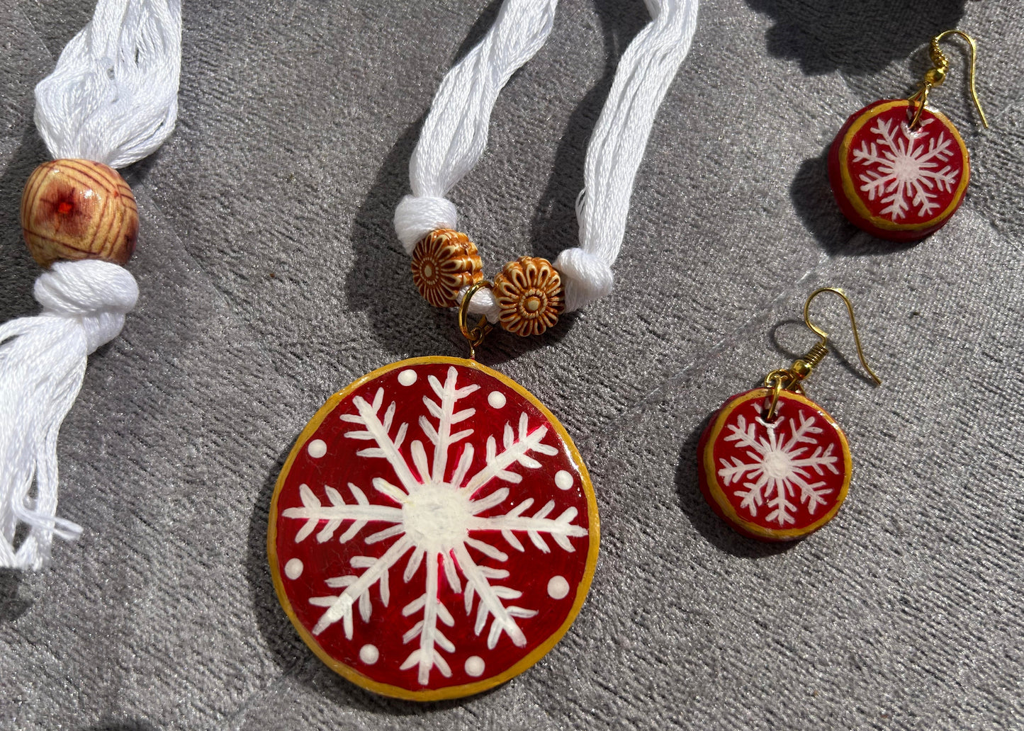 Necklace and earrings with snowflake design on a gray surface