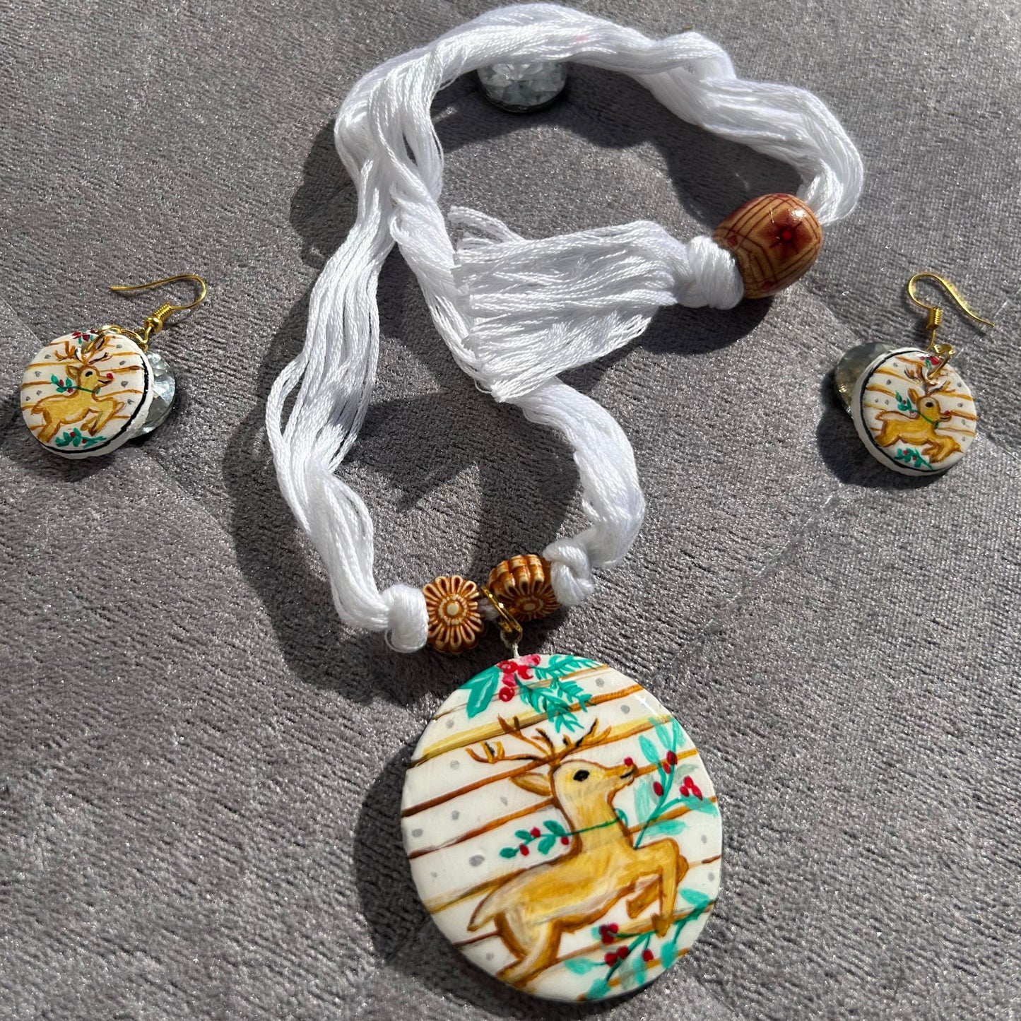 Jewelry set with a bracelet and earrings featuring deer designs on a stone surface.