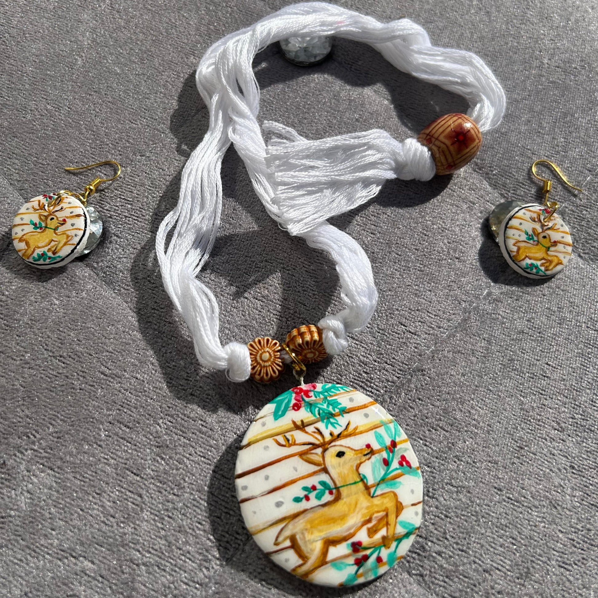 Jewelry set with a bracelet and earrings featuring deer designs on a stone surface.
