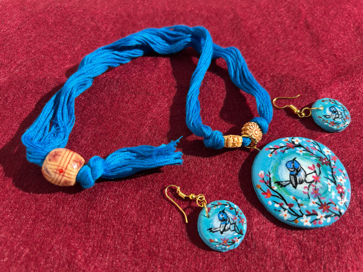Blue jewelry set with bracelet and earrings on a red background