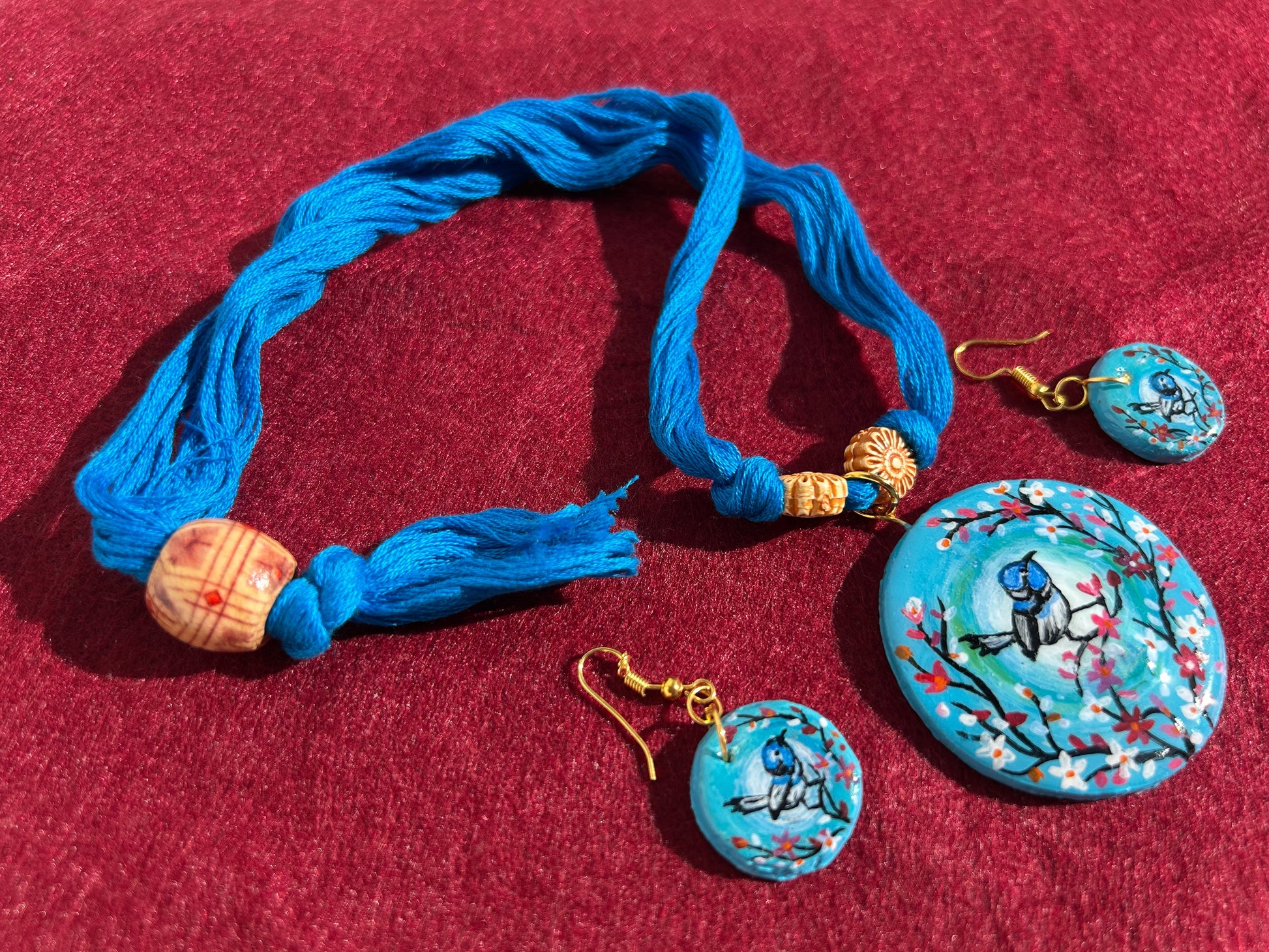 Blue jewelry set with bracelet and earrings on a red background