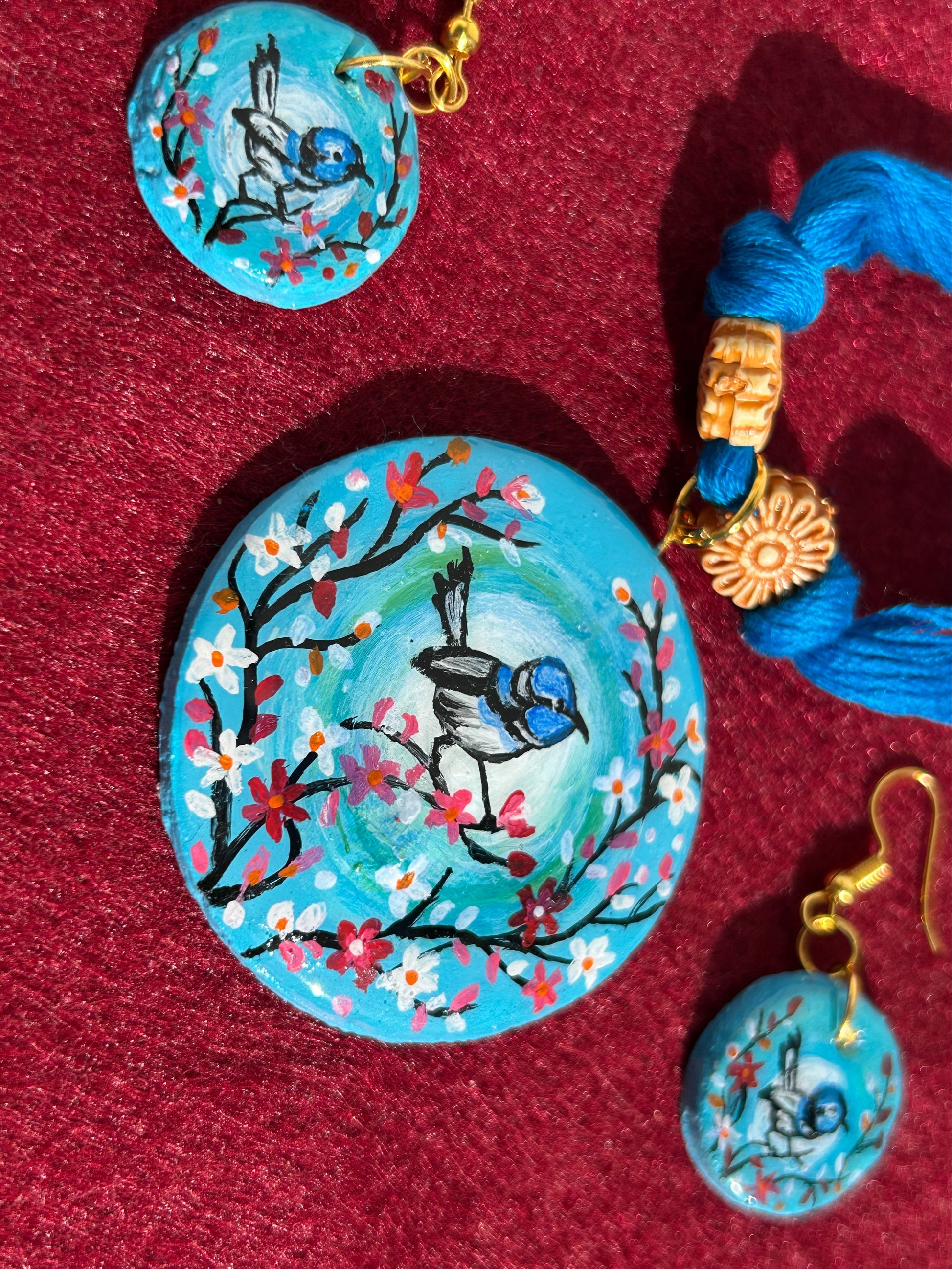 Set of blue jewelry with bird designs on a red fabric background
