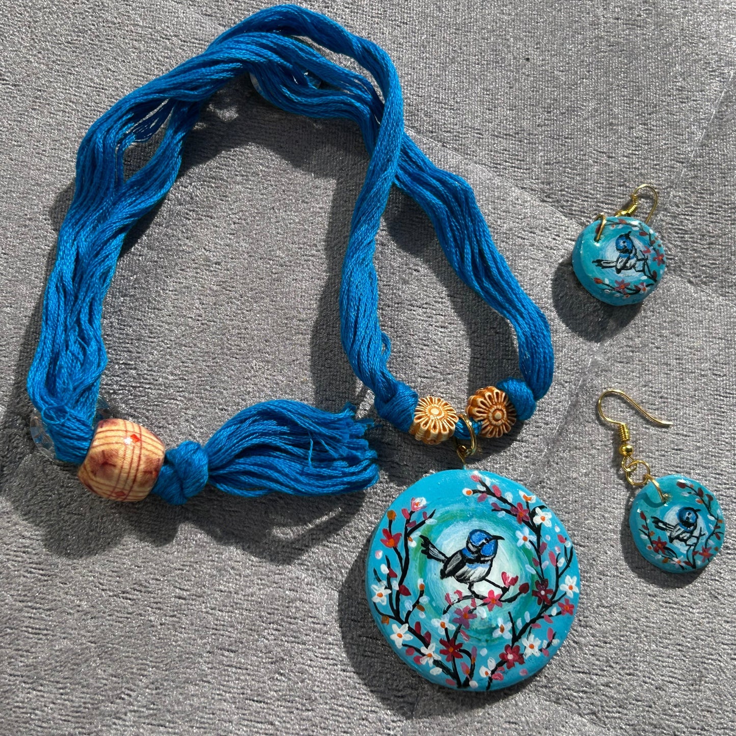 Blue necklace with matching earrings on a gray surface