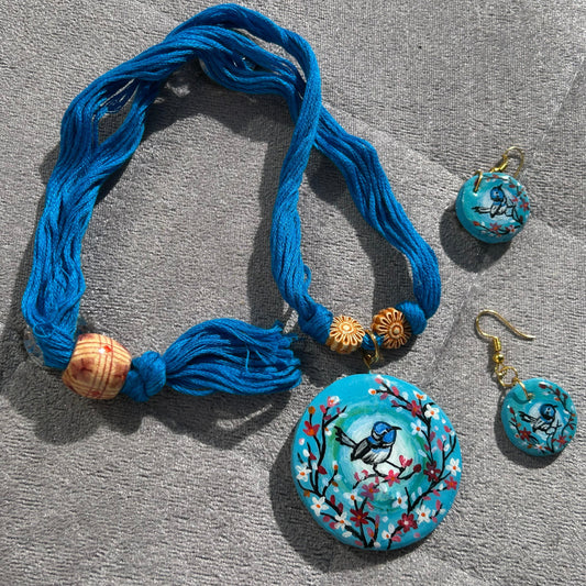 Blue necklace with matching earrings on a gray surface