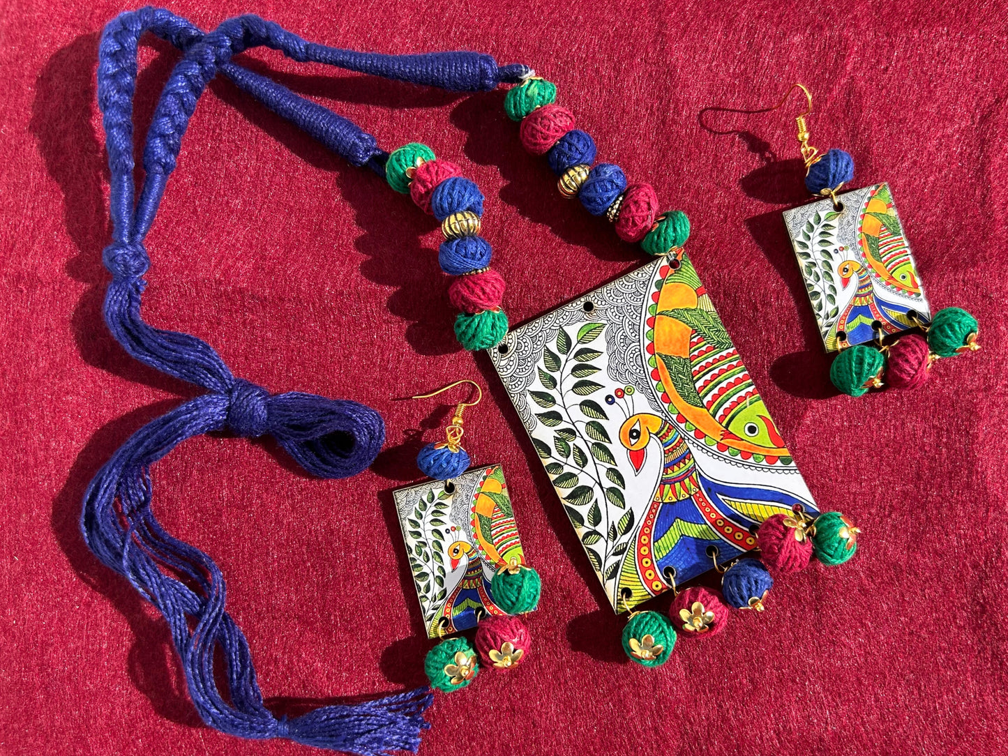 Colorful jewelry set with necklace and earrings on a red surface