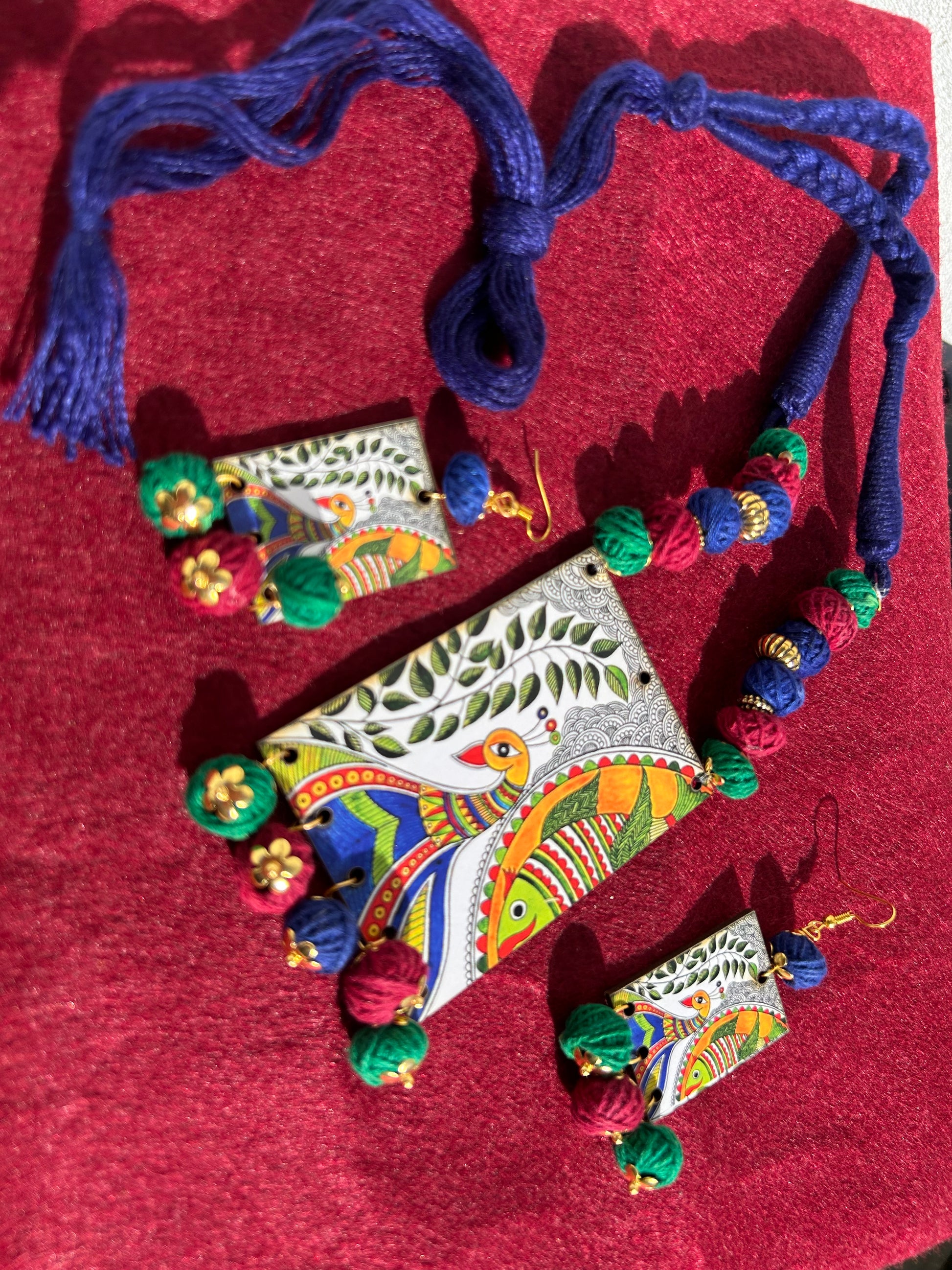 Colorful jewelry set with necklace and earrings on a red fabric background