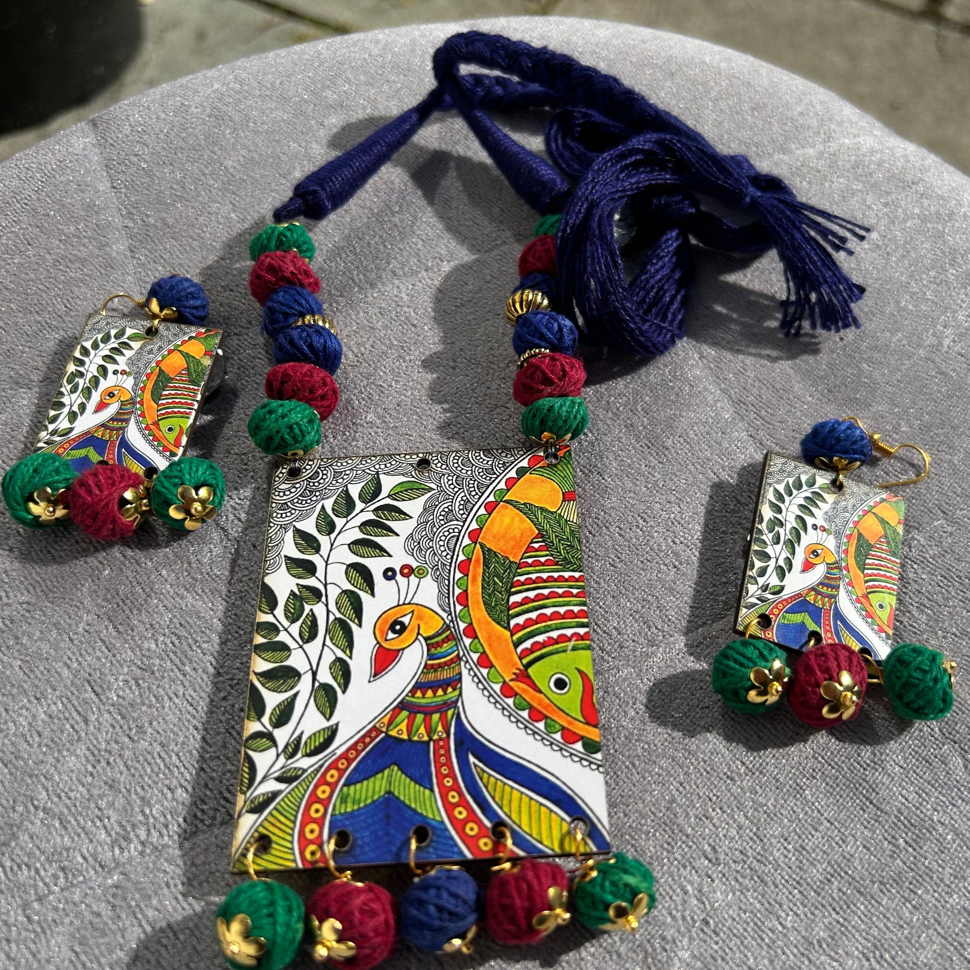 Colorful jewelry set with a necklace and earrings on a gray surface.