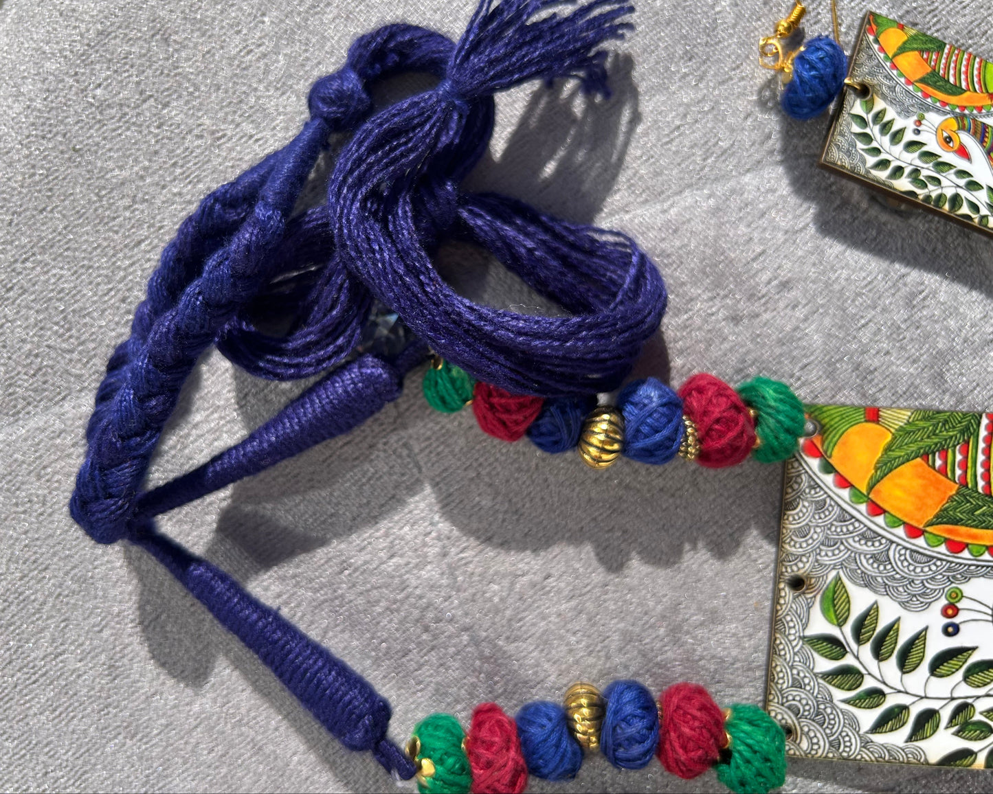 Decorative blue cord with colorful beads on a textured surface