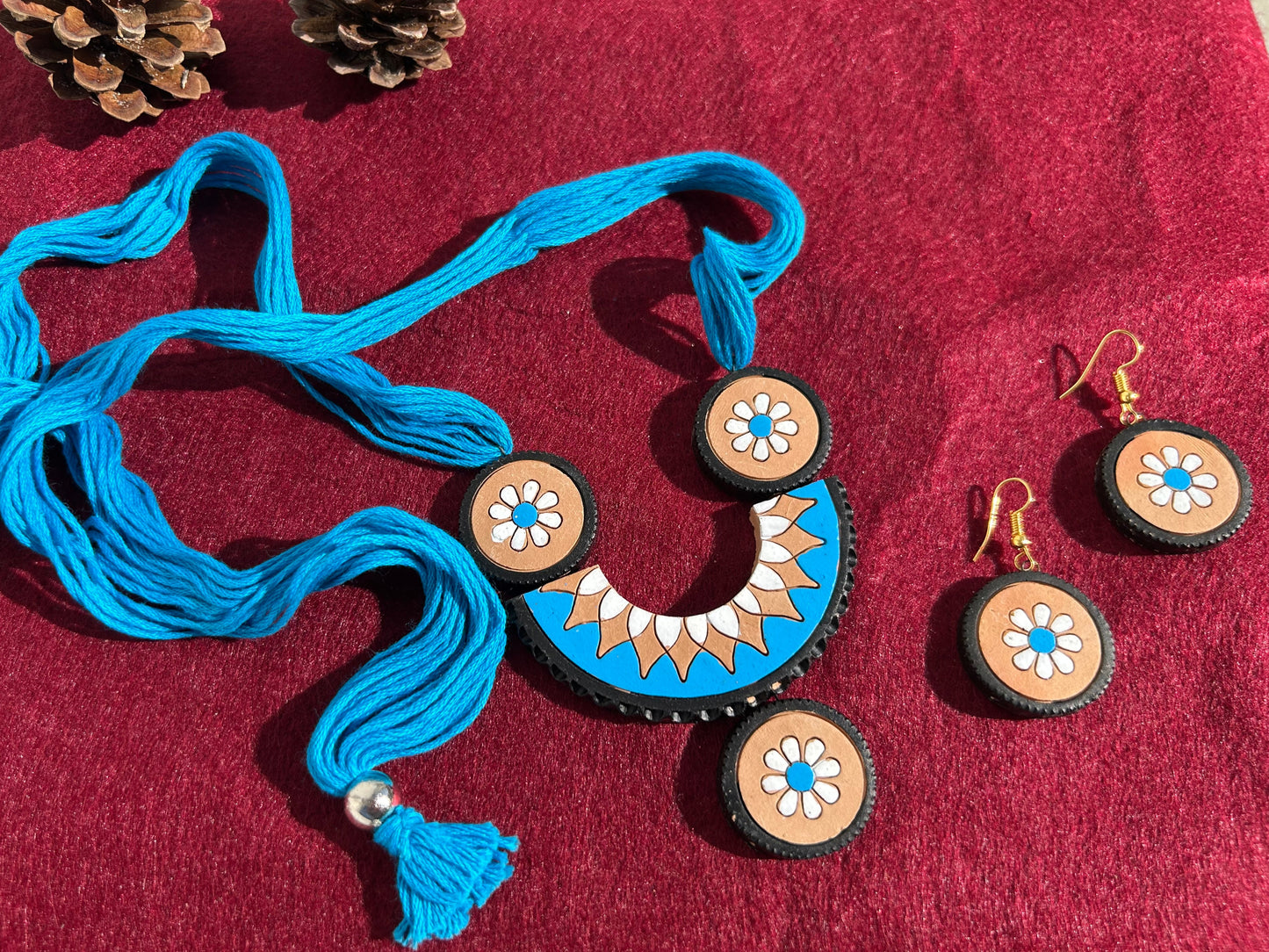 Blue necklace with tassels and matching earrings on a red fabric background