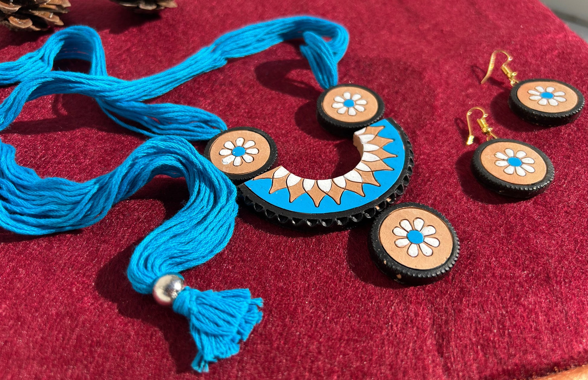 Jewelry set with blue tassel necklace and matching earrings on a red fabric background