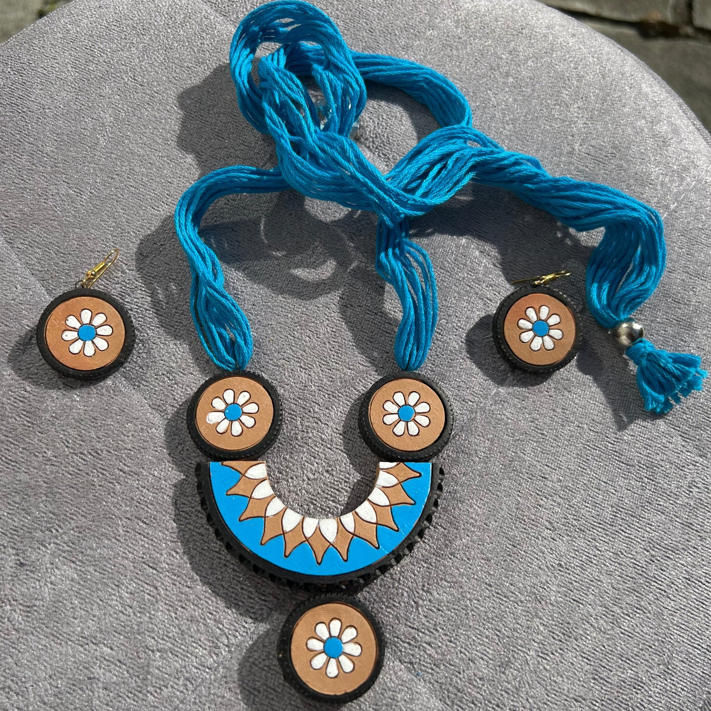 Blue necklace with terracotta beads on a gray surface