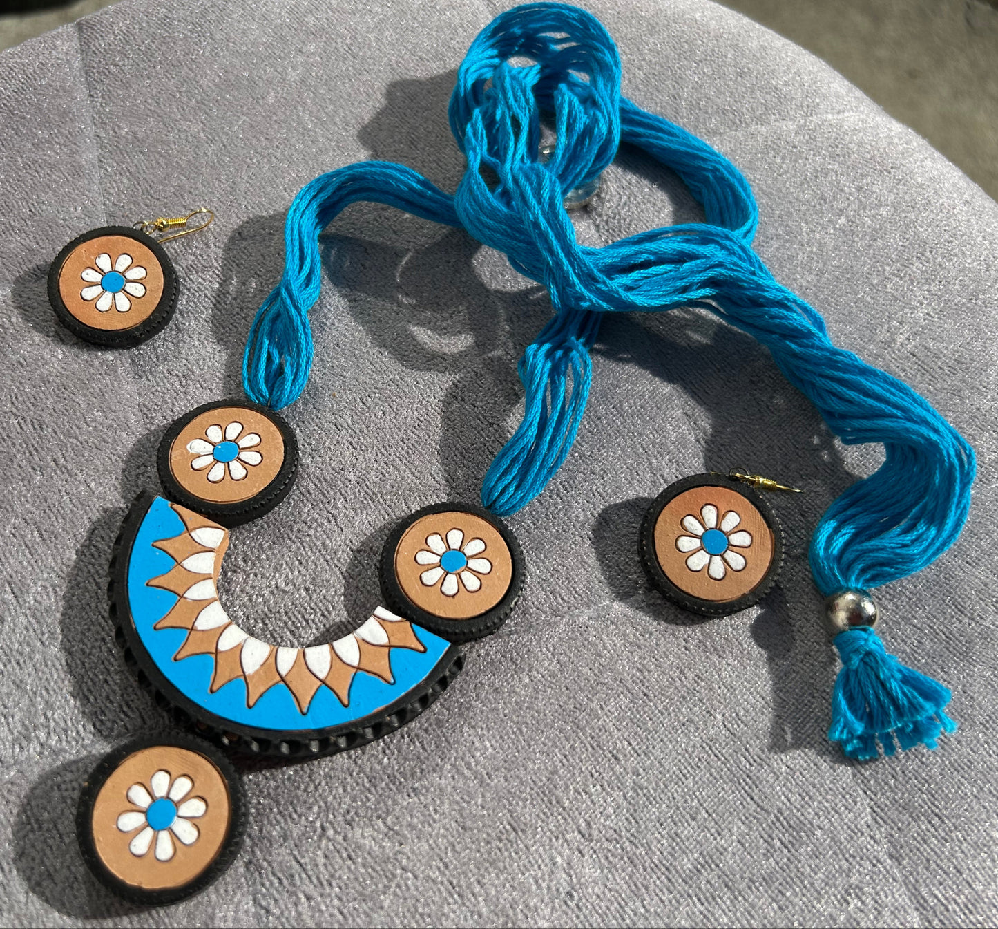 Jewelry set with blue necklace and earrings on a beige surface