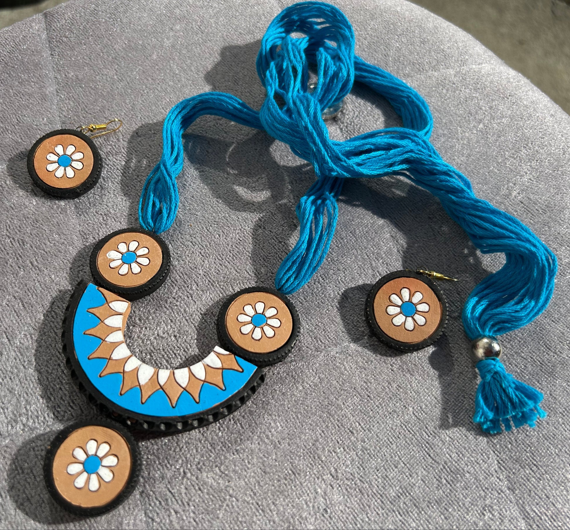 Jewelry set with blue necklace and earrings on a beige surface