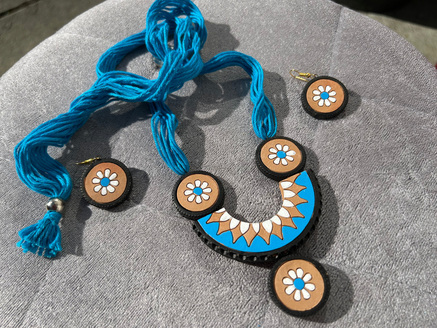 Jewelry set with blue necklace and wooden earrings on a textured surface