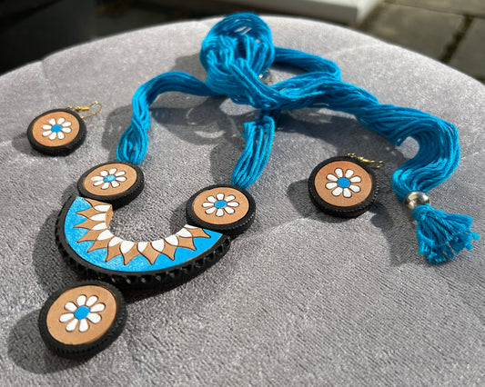 Necklace and earrings with blue cord on a gray surface