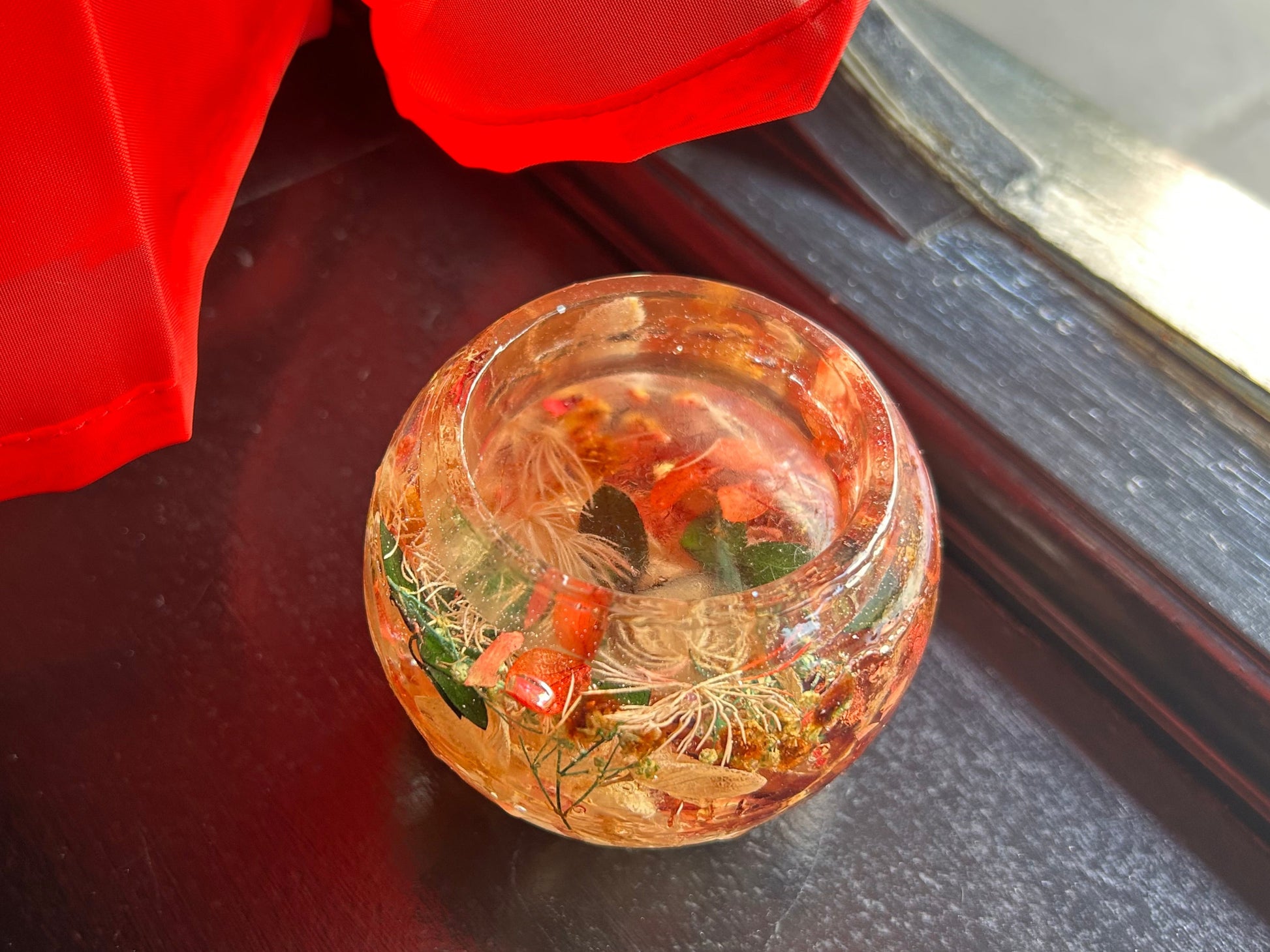 Decorative glass ball with floral elements on a dark surface