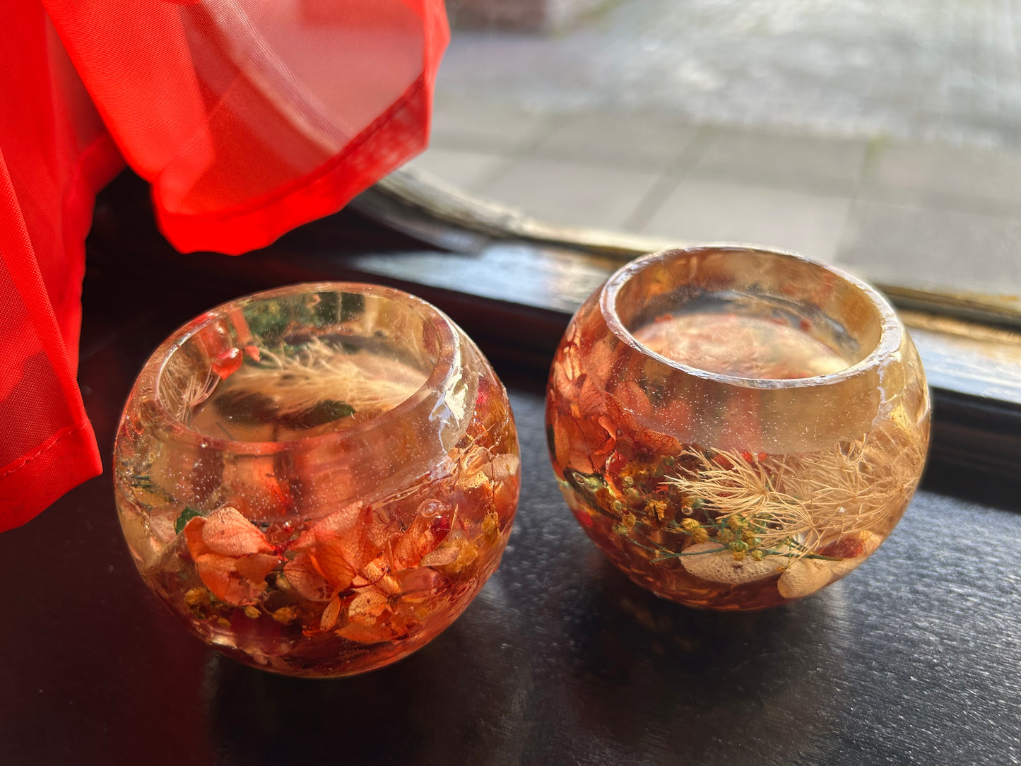 Two small glass containers with decorative elements on a dark surface.
