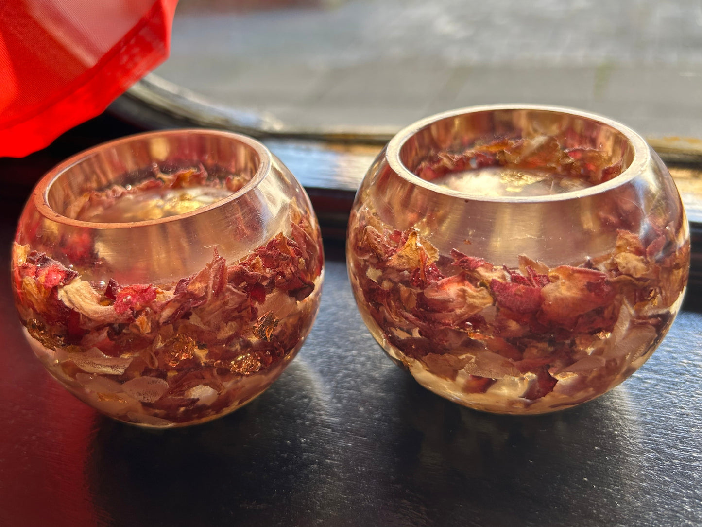 Two resin holders with a floral or herb-like interior on a dark surface.