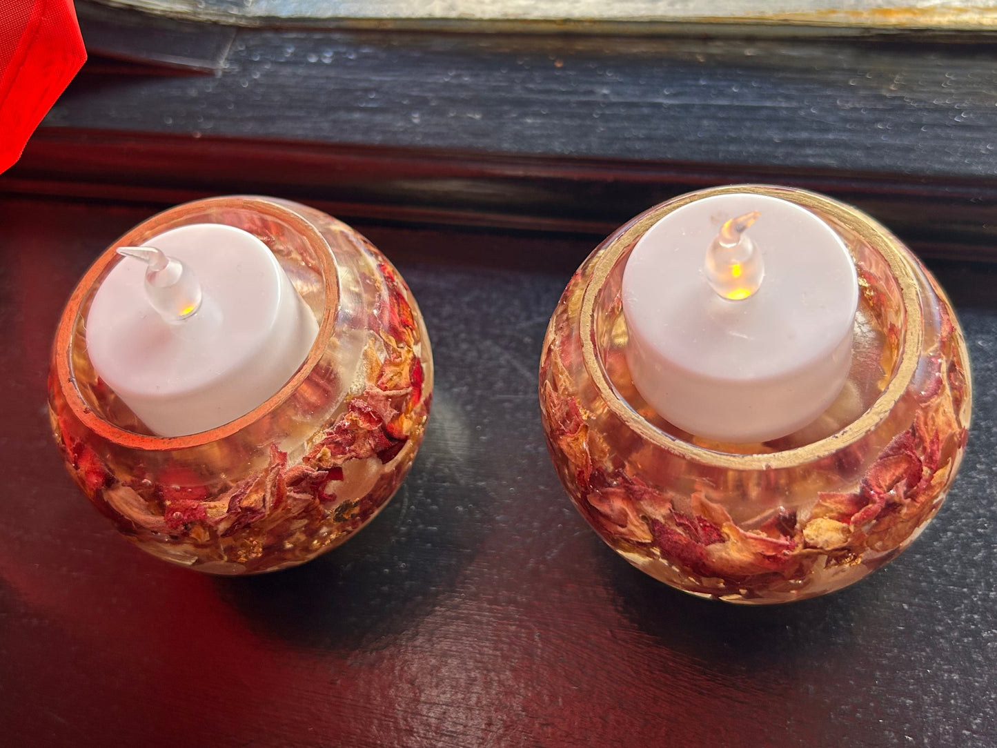 Two small candles in decorative holders on a dark surface.