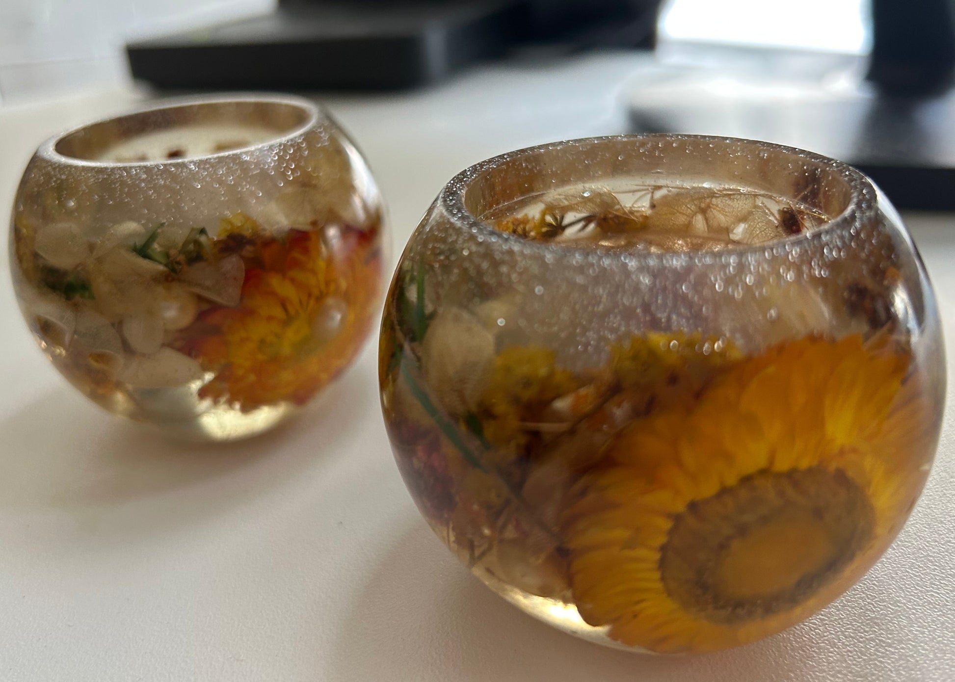Two glass containers with sunflower designs on a desk.