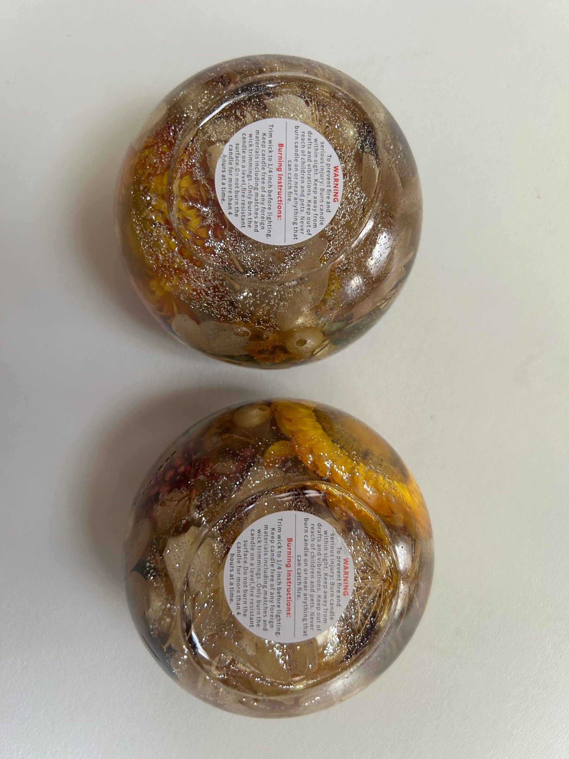 Two glass jars with decorative contents and labels on a white background