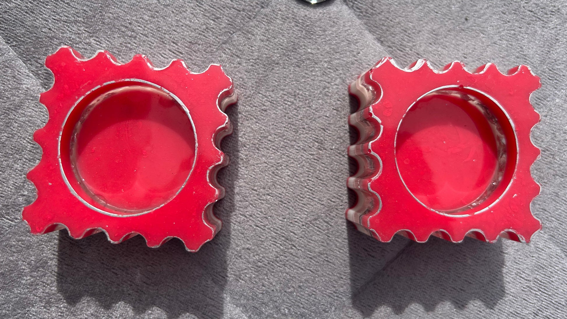 Red gear-shaped earrings on a gray surface