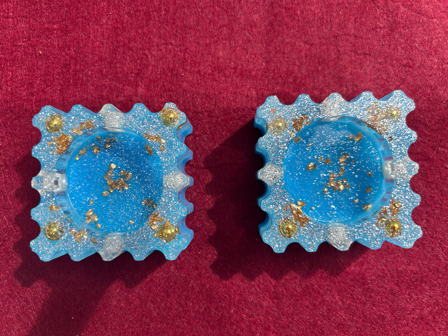 Pair of blue earrings with gold accents on a red background