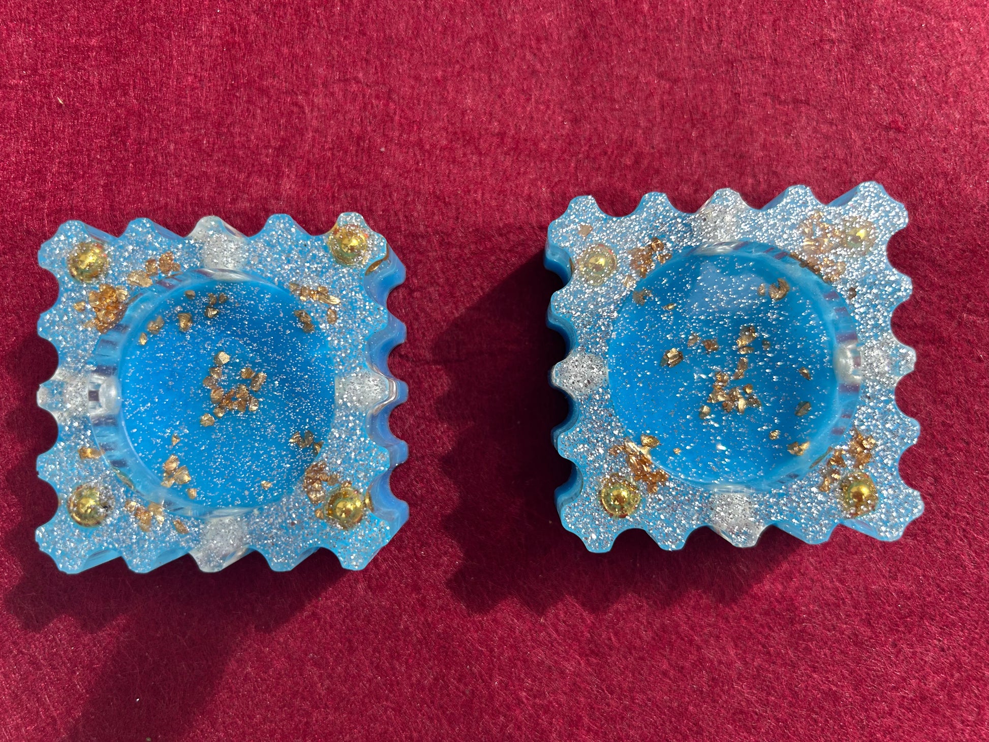 Pair of blue earrings with gold accents on a red background