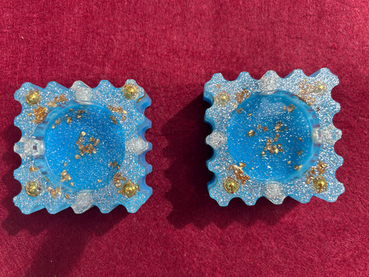 Pair of blue earrings with gold accents on a red background