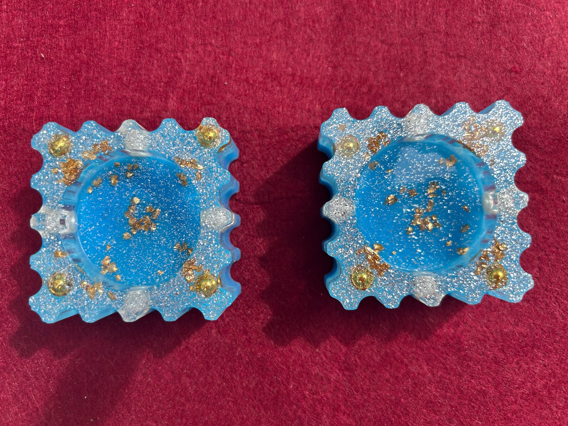 Pair of blue earrings with gold specks on a red background