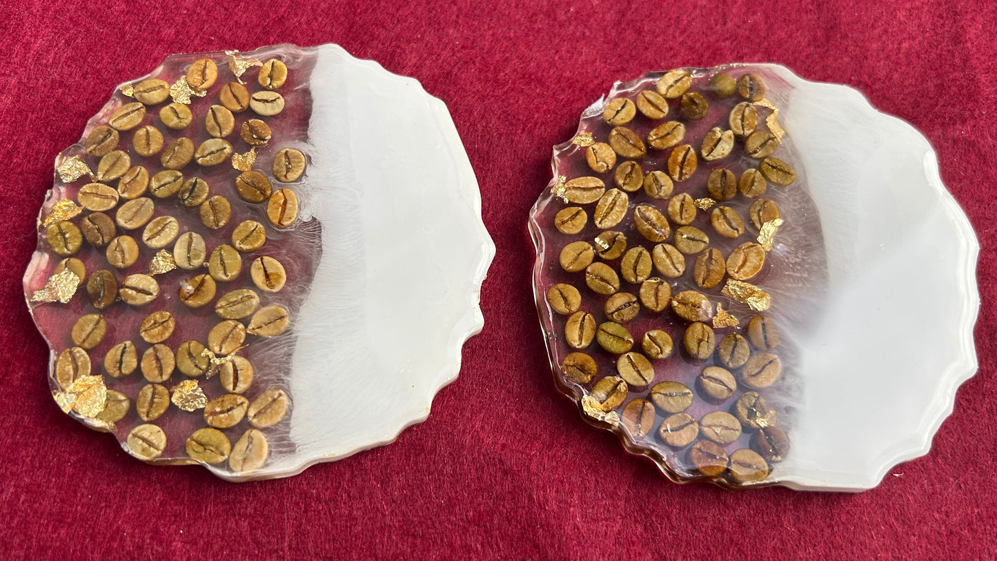 Two shell-shaped objects with embedded gold-colored seeds on a red fabric background