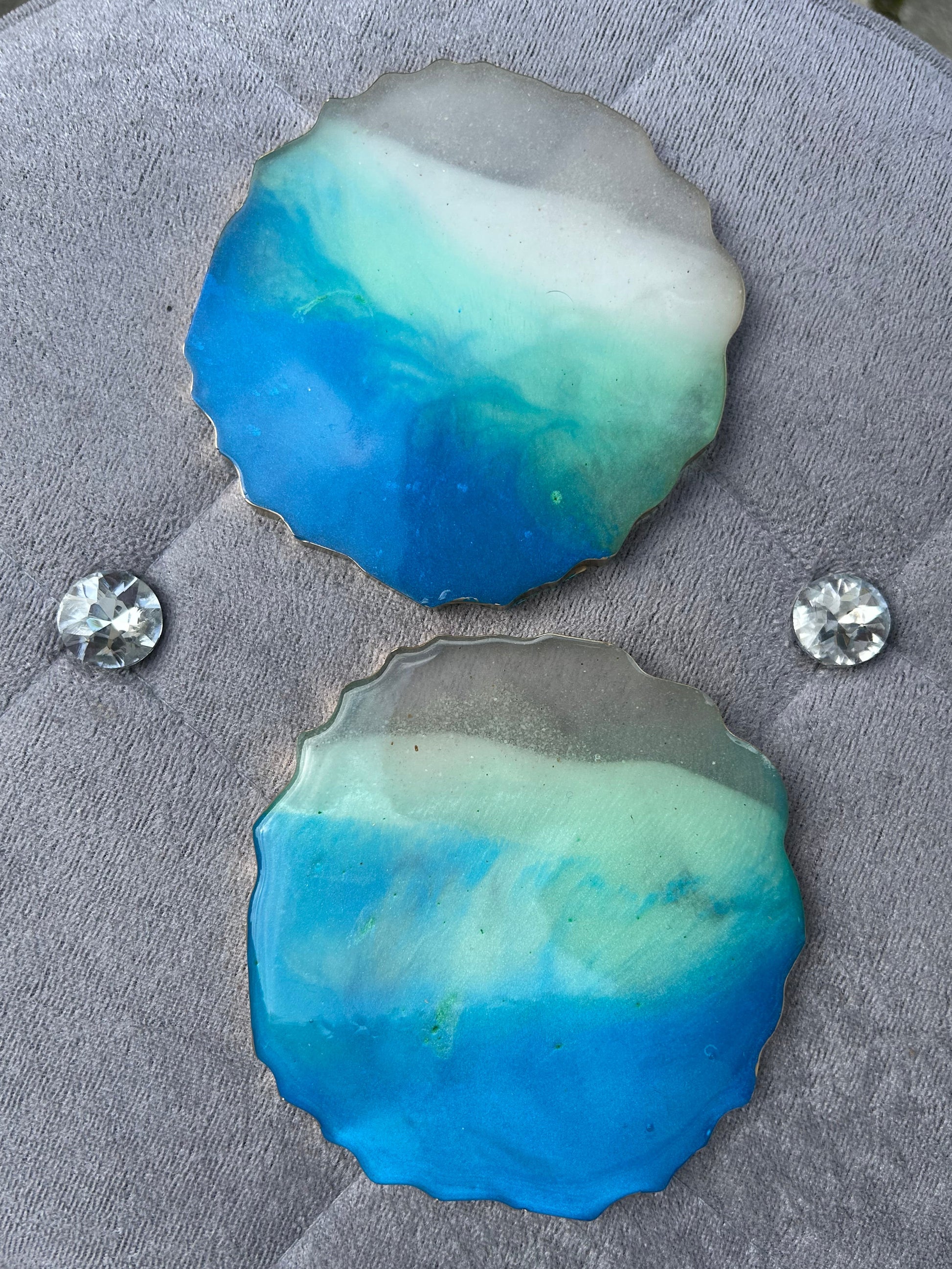 Blue and green stone with two clear crystals on a gray textured surface