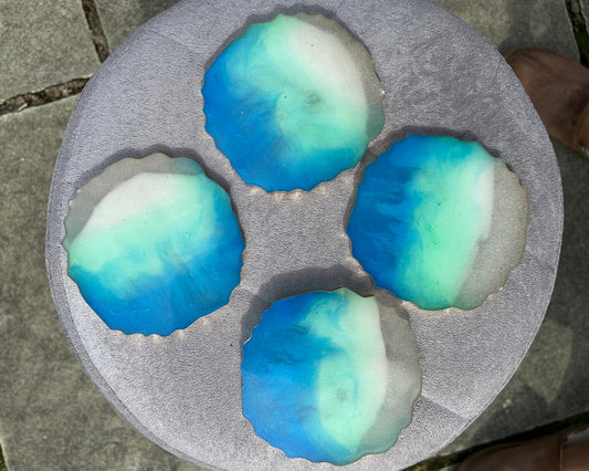 Three blue and green spherical objects on a gray surface